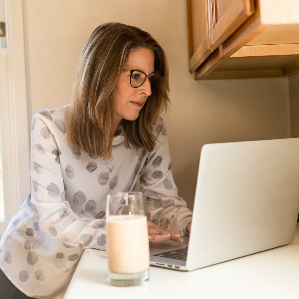 Woman Using Laptop with Glass of Milk