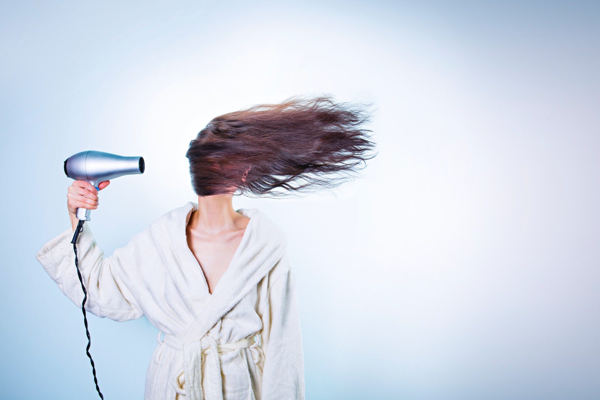 A woman in a bathrobe drying her hair.