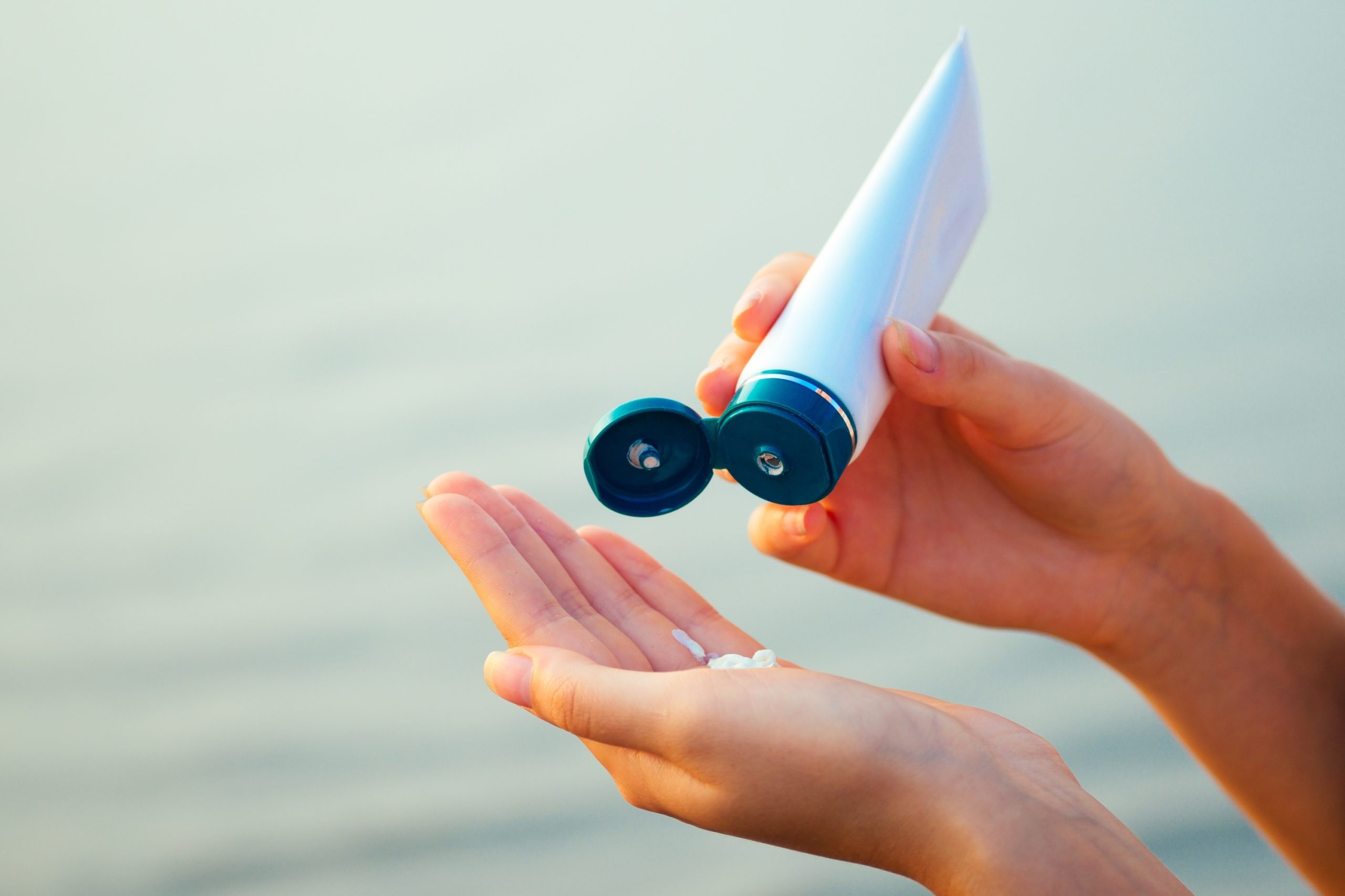 person squeezing sunscreen tube in their hands