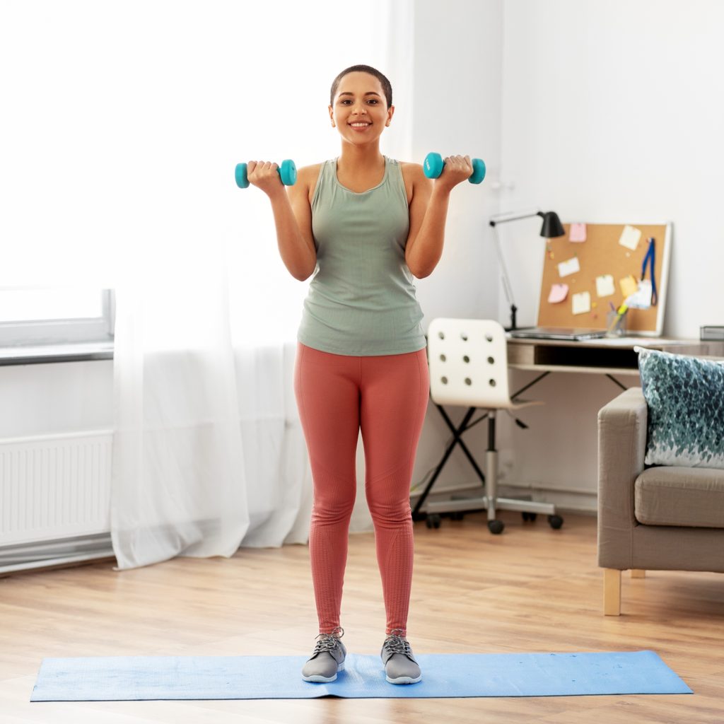 woman performing bicep curls in living room