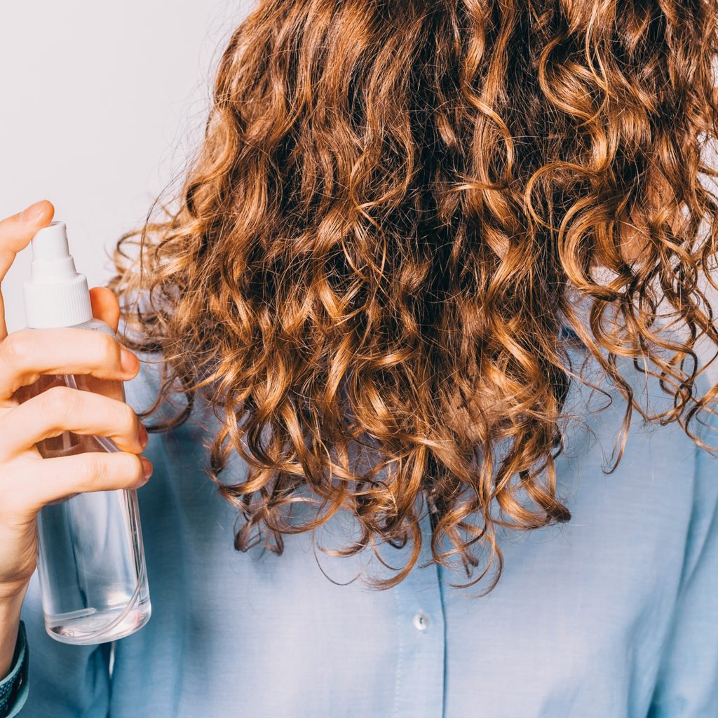 girl spraying her curls with sea salt spray