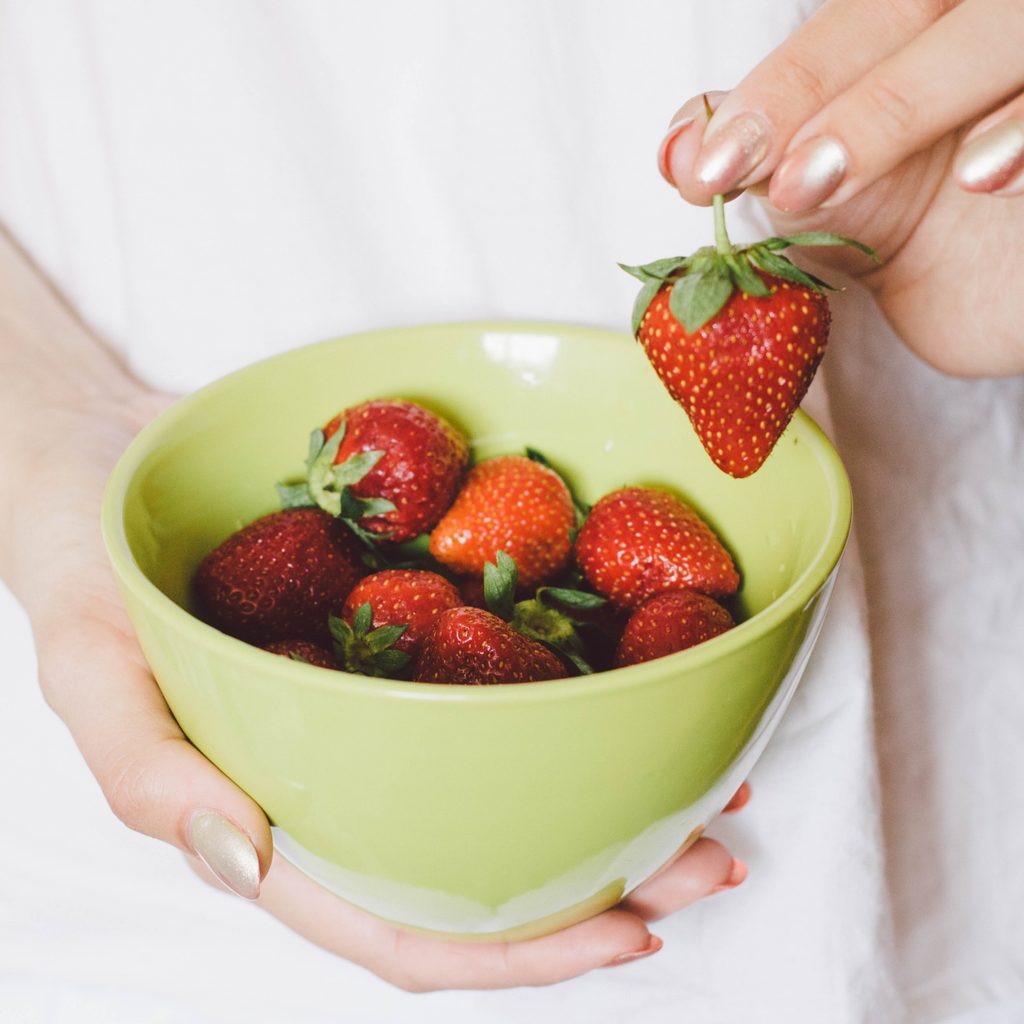 person holding strawberries in bowl