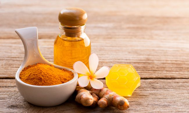 turmeric powder and oil on table with flower