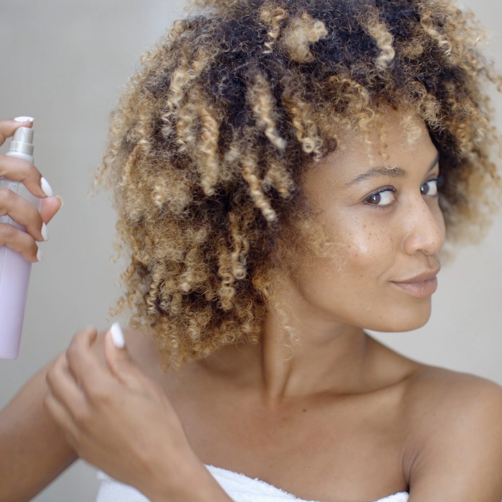 woman applying sea salt spray to hair