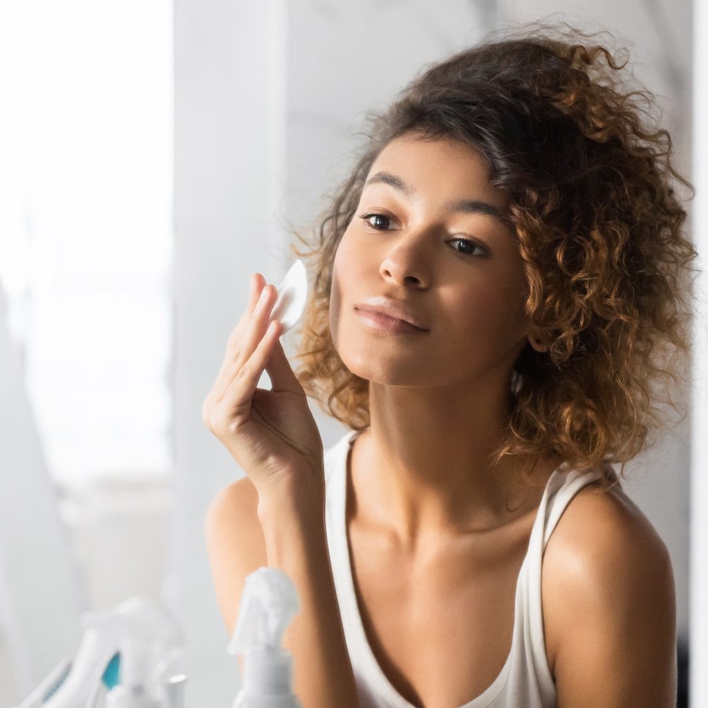 woman removing makeup in mirror