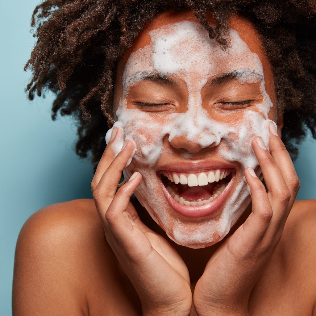 young woman with foam on her face during skincare routine