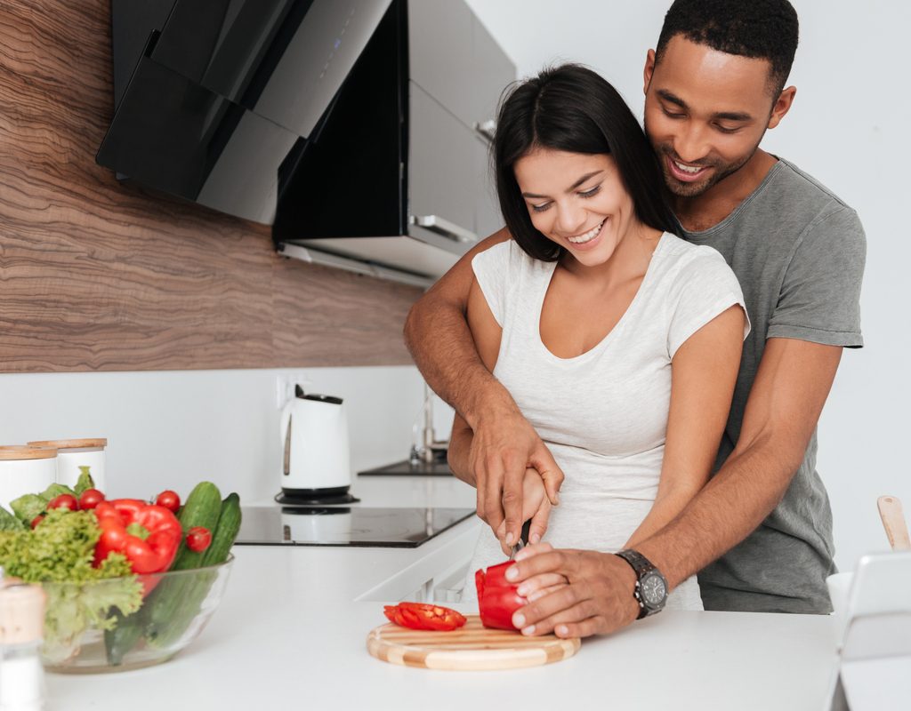 A couple chops a tomato