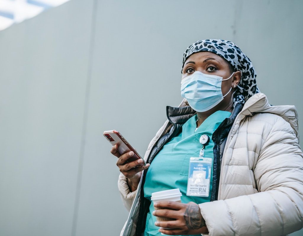Healthcare worker wearing her mask with her iPhone in her hand