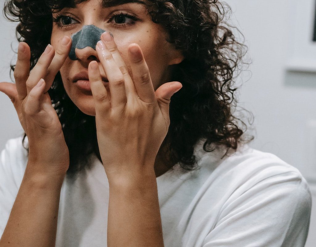 A woman applying skin care to her nose
