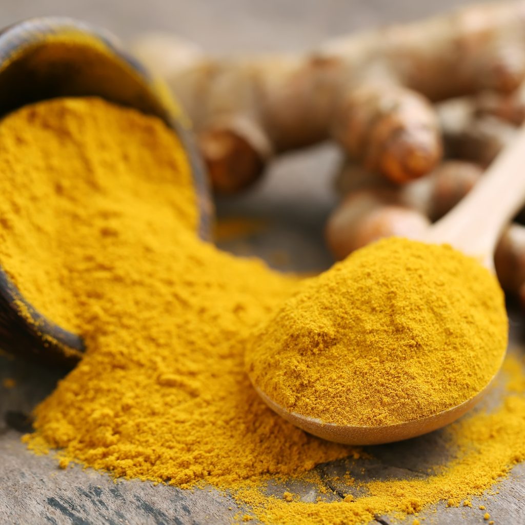 turmeric powder with spoon and bowl spilled