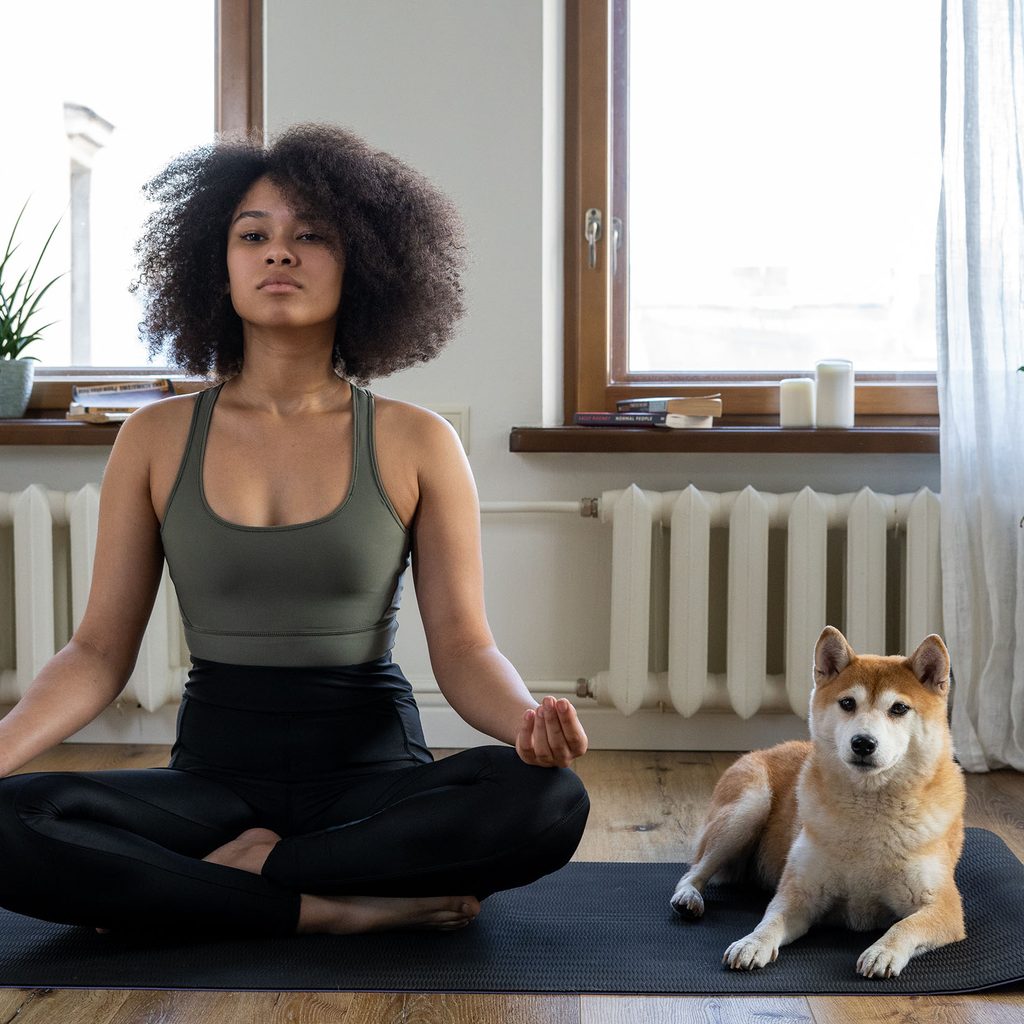 Woman doing yoga at home with her dog