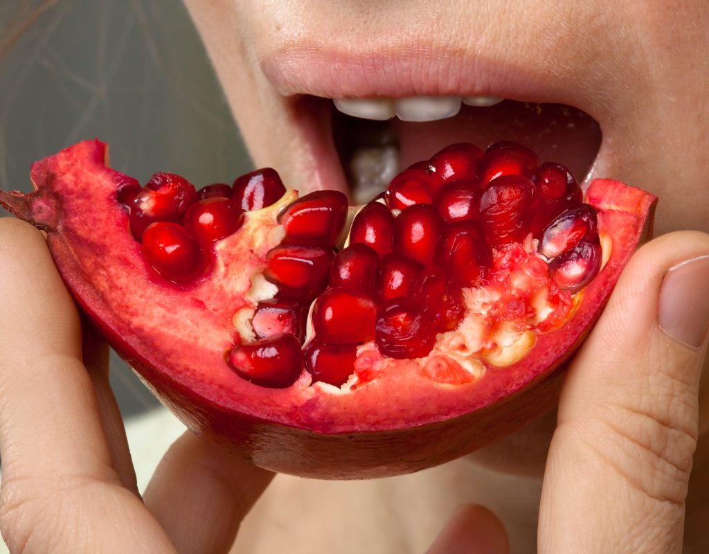 A woman eats a pomegranate