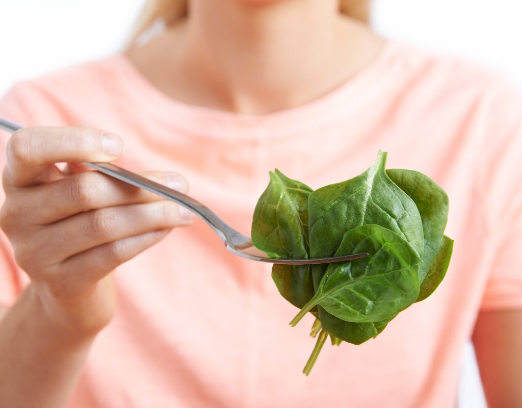 A woman eats spinach