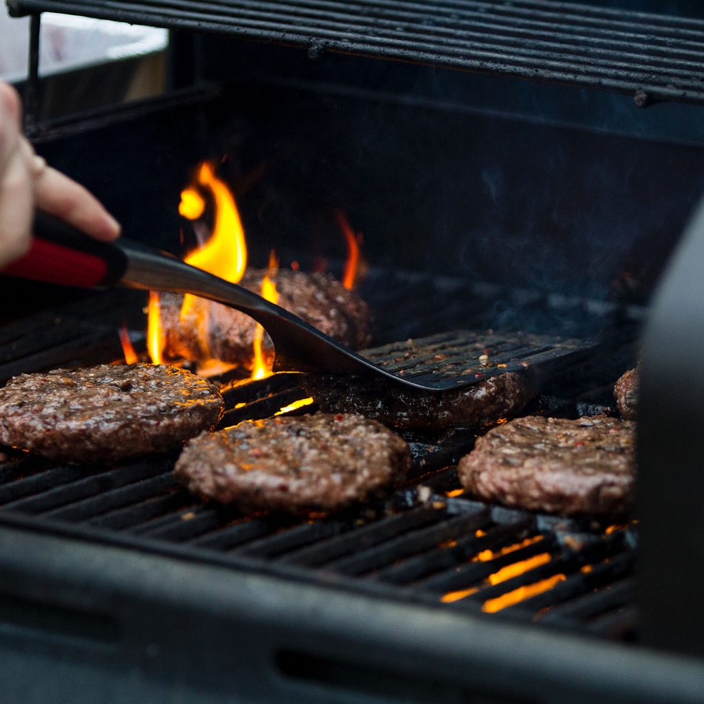Person cooking burgers on a grill