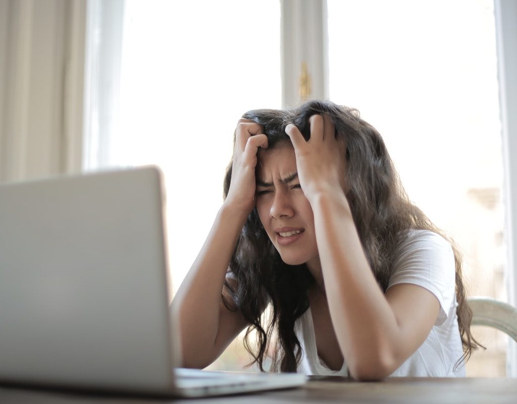 A woman holding her head being stressed out.