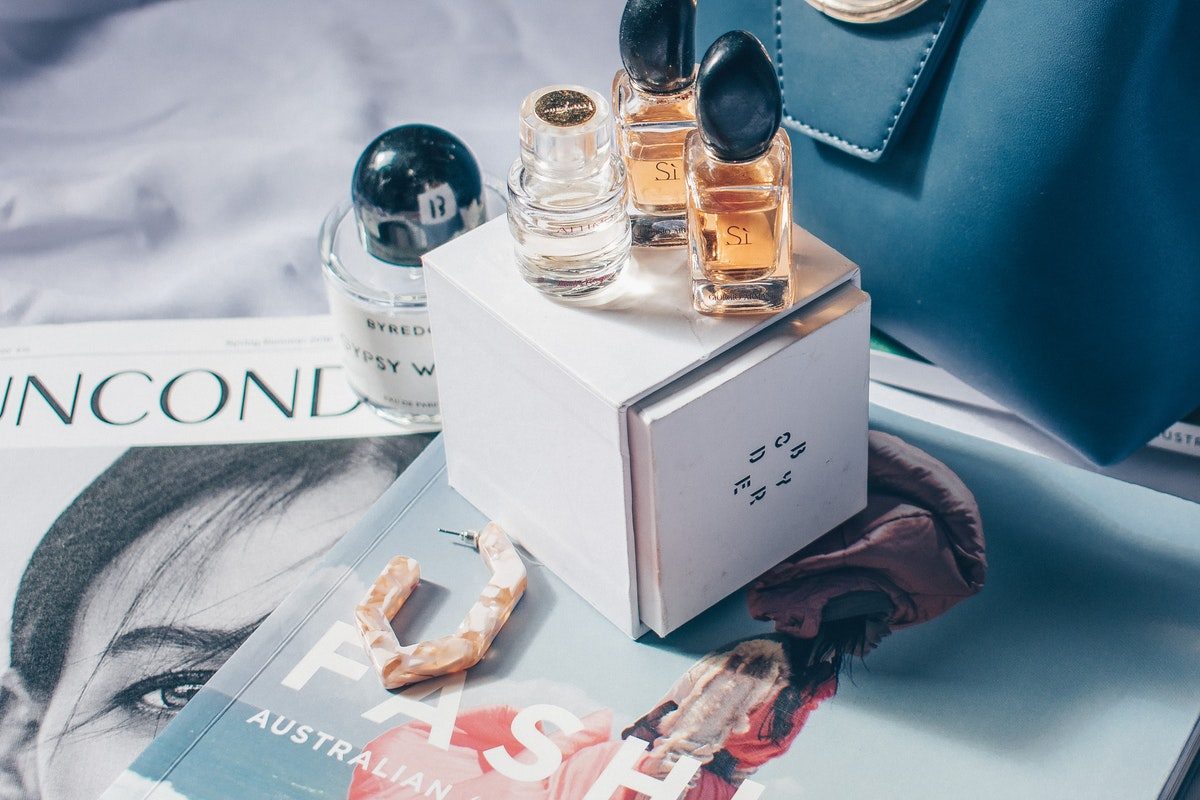 Perfume bottles displayed on a box that is on top of magazines.
