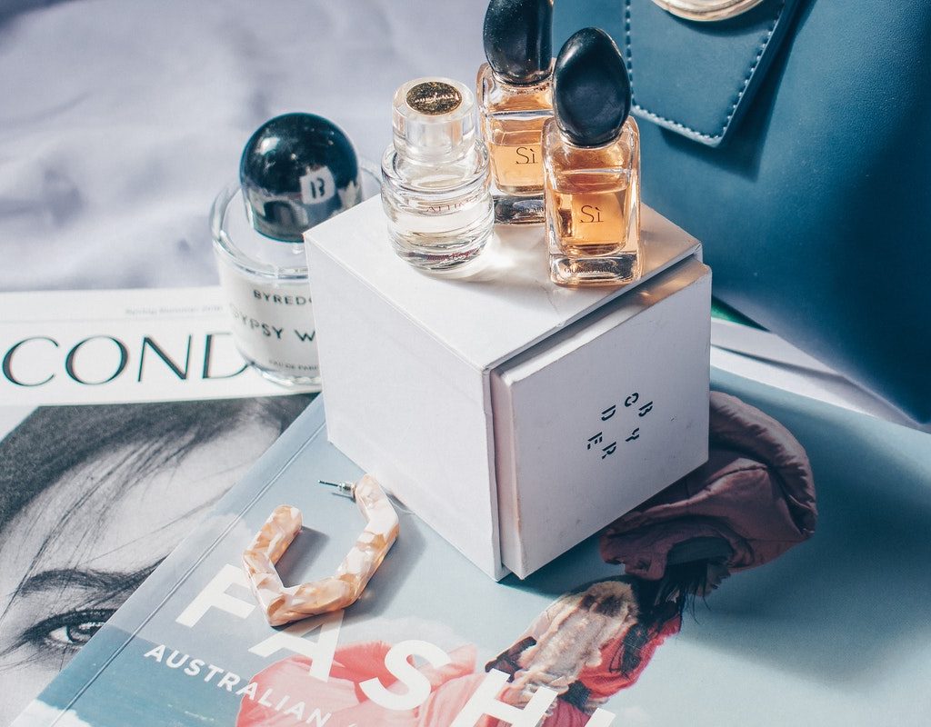 Perfume bottles displayed on a box that is on top of magazines.