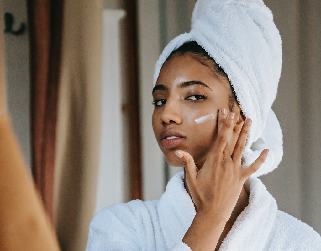 A woman putting on face cream.