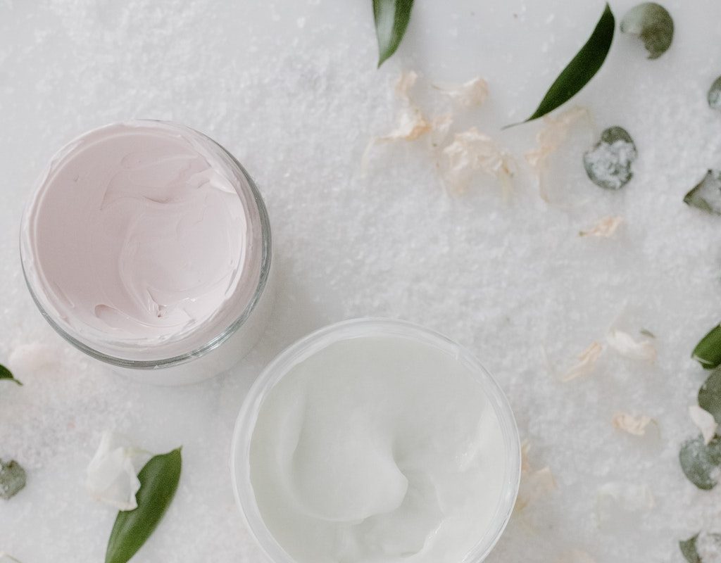 Two jars of skin care products on a table.