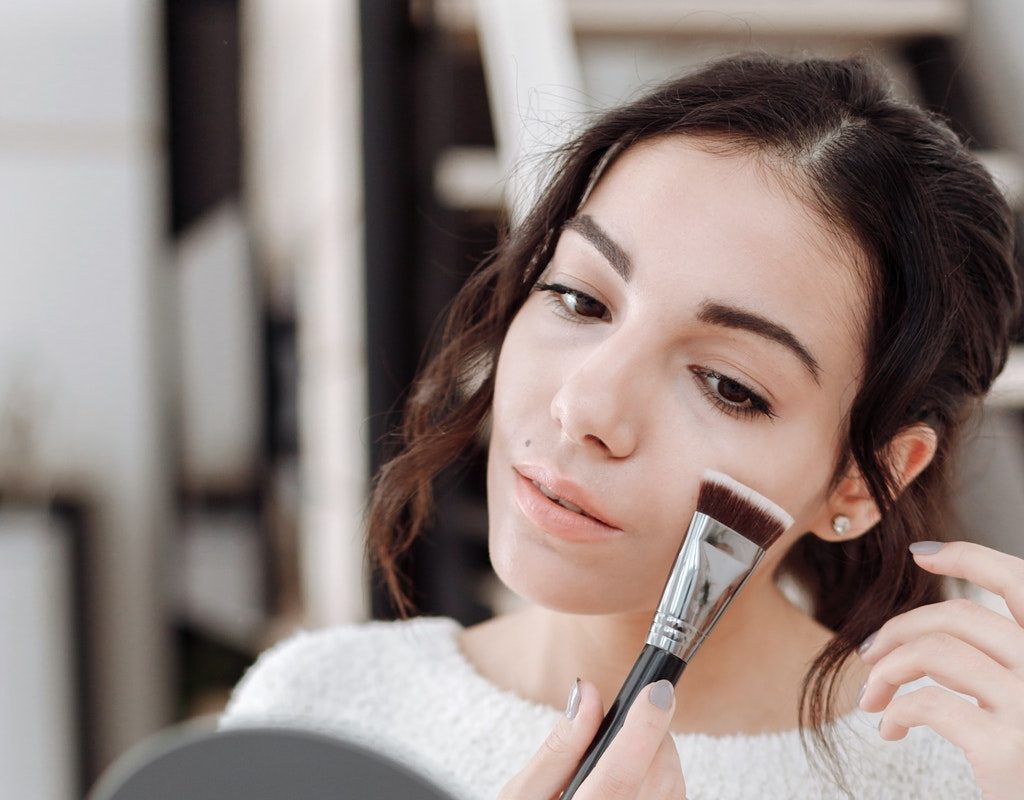 A woman putting on makeup in front of a mirror.
