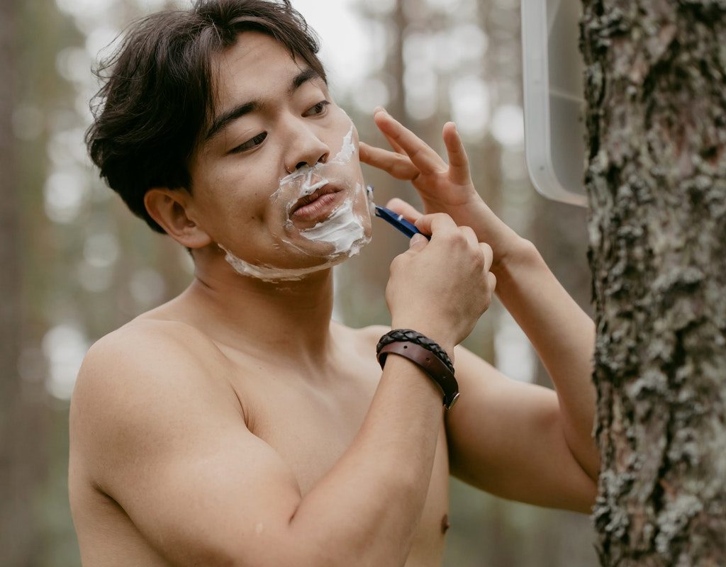 A man shaving his face outside.