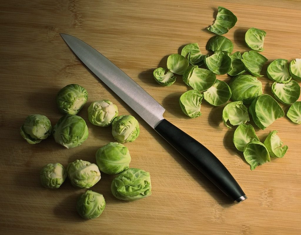 Brussels sprouts on a table with a knife.