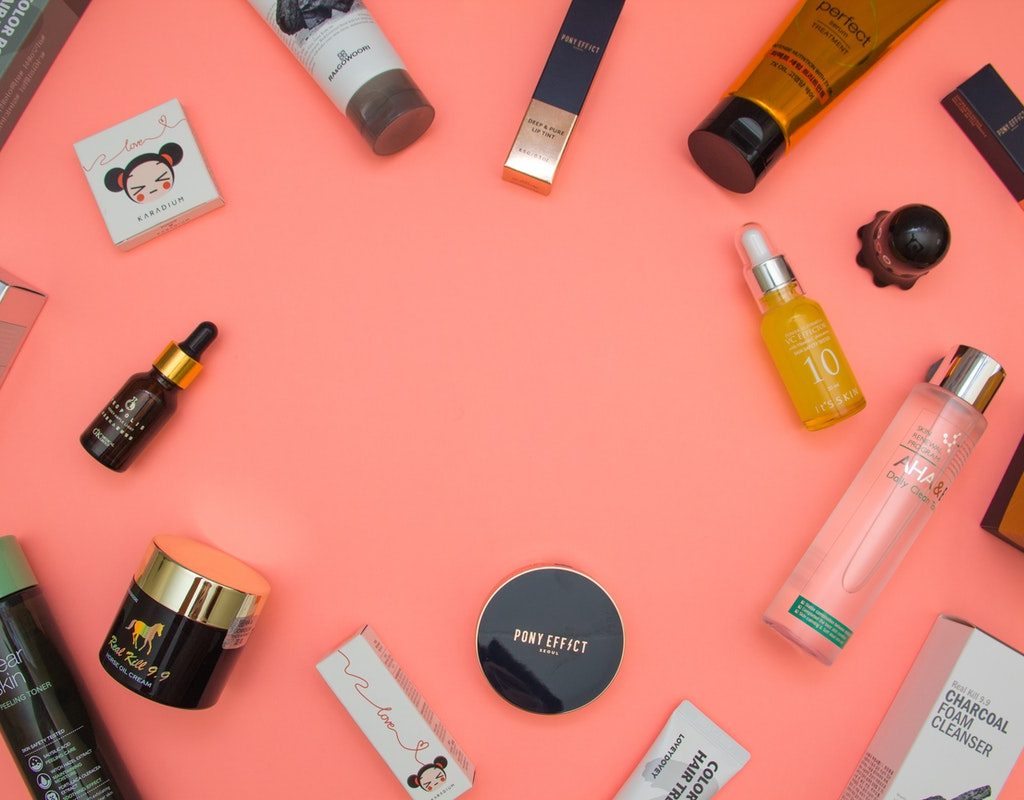 A bunch of beauty products on a pink table.