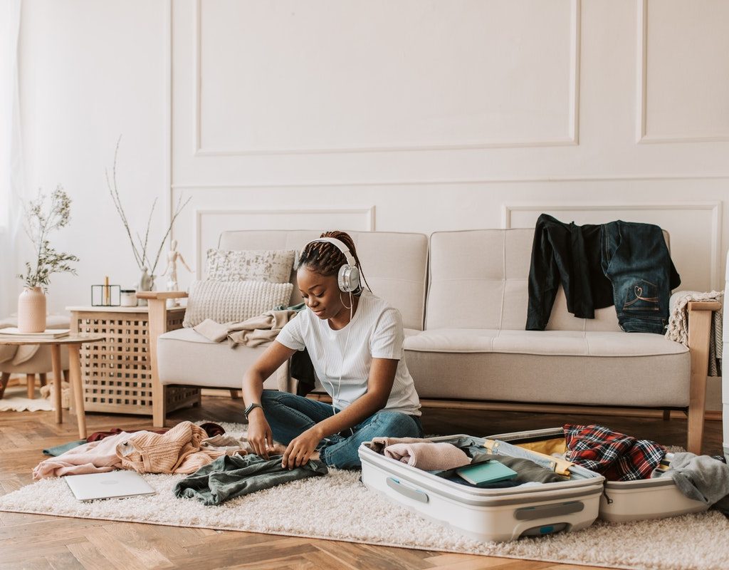 A woman is packing her suitcase while listening to music.