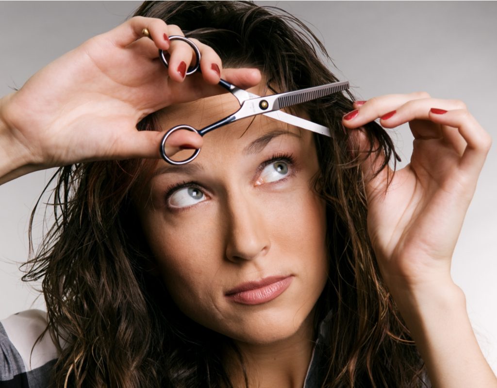 A woman cutting her own bangs.