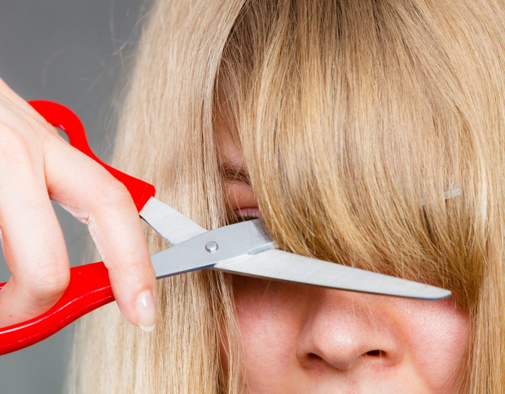 A woman cutting her own bangs.