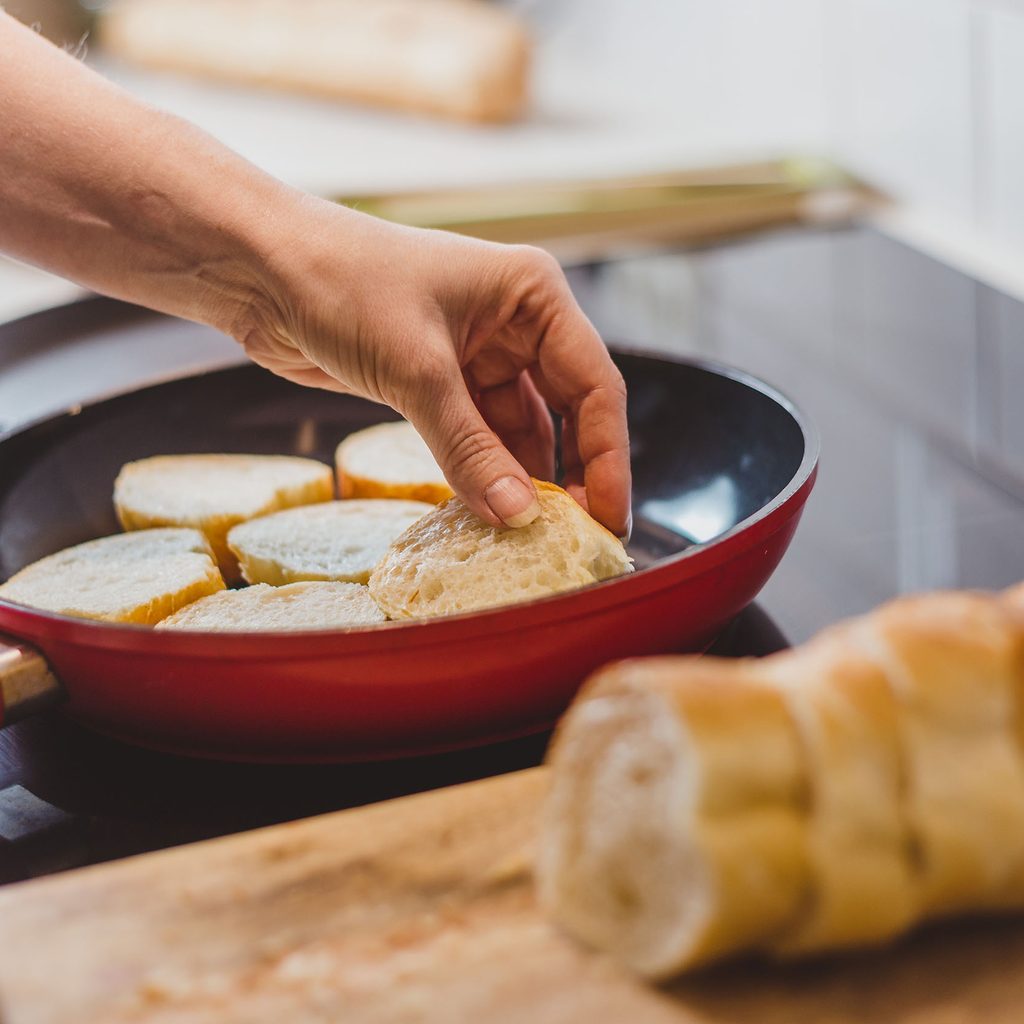 Person frying French bread in pan