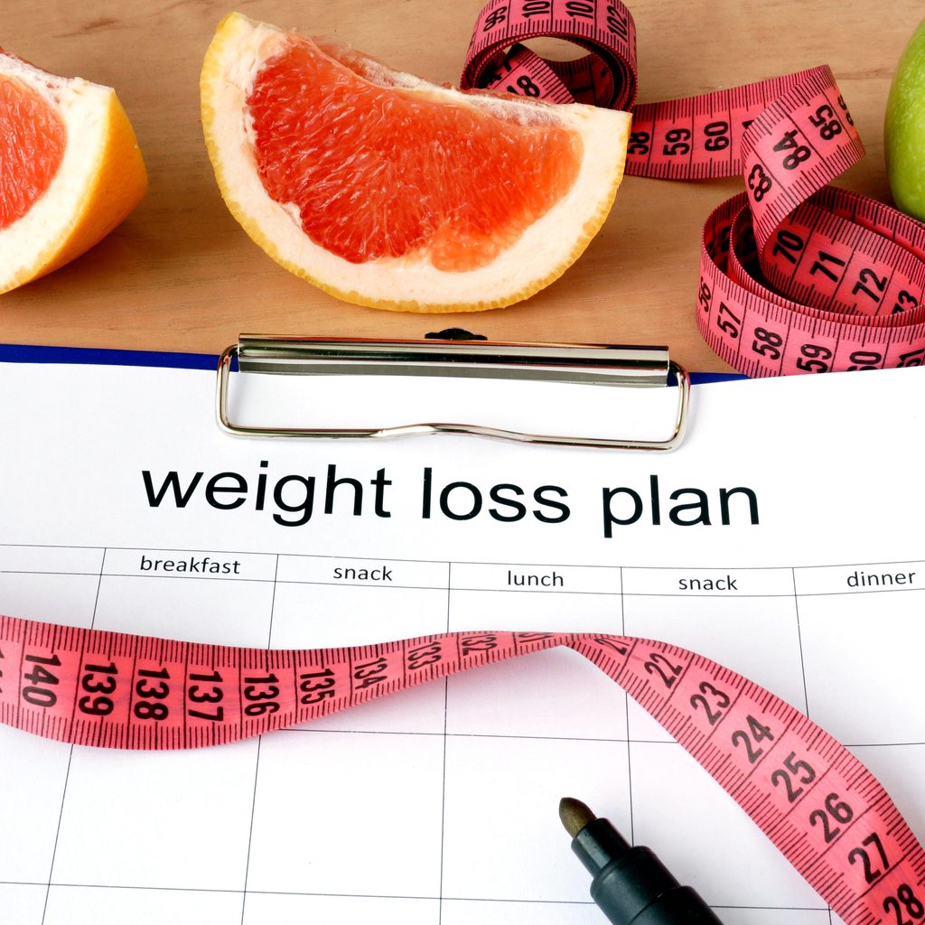 weight loss plan sheet with tape measure and fruit