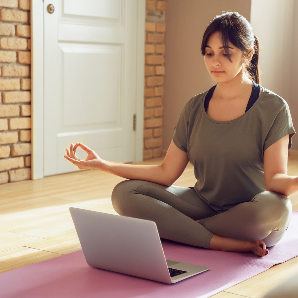 woman doing yoga in front of laptop