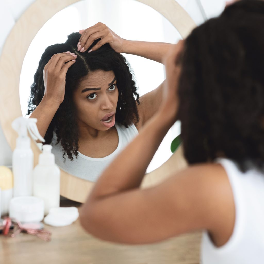woman looking at scalp in mirro