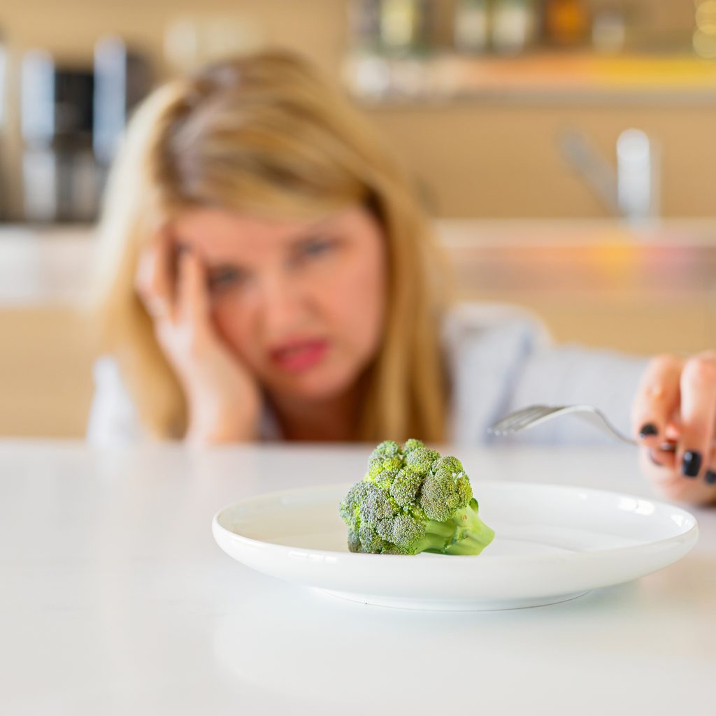 woman upset one piece of broccoli on plate