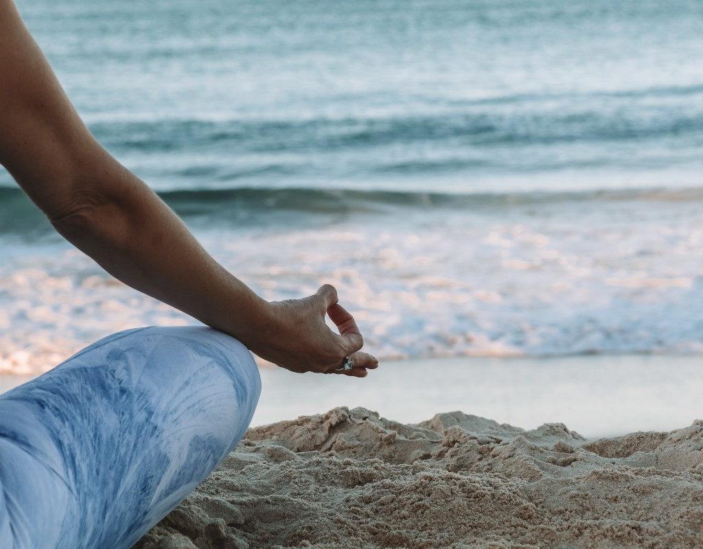 a person meditating in the sand by the ocean