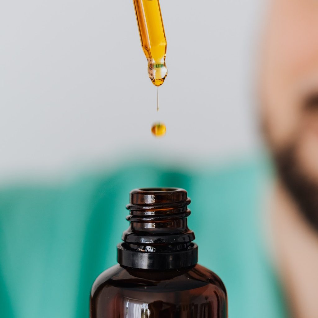 A dropper dropping oil into the glass container.