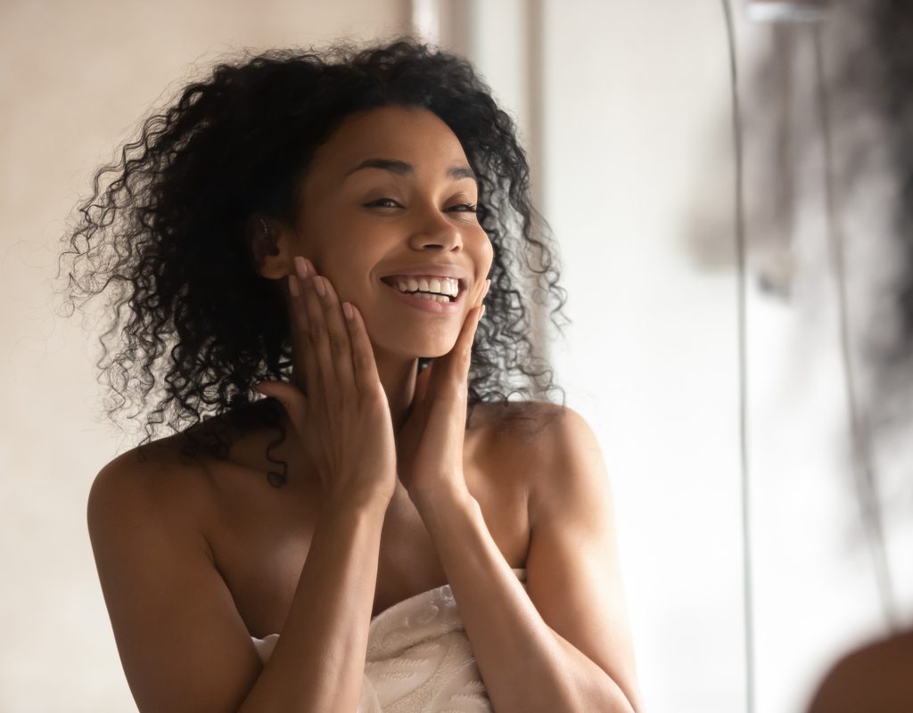 A happy woman looking at herself in the mirror.