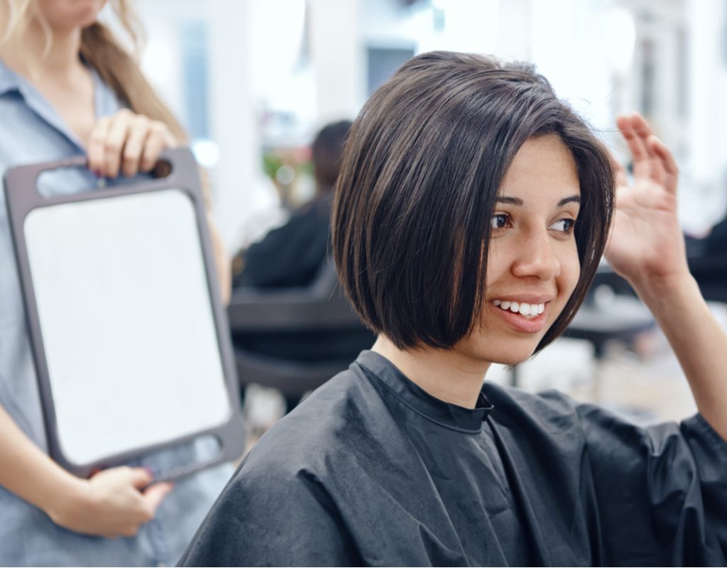 A stylist showing a woman the back of her haircut.
