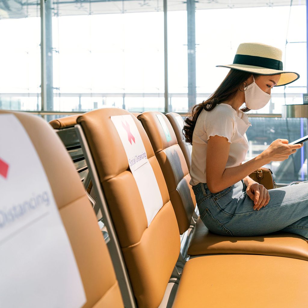 Woman wearing a mask sitting at the airport