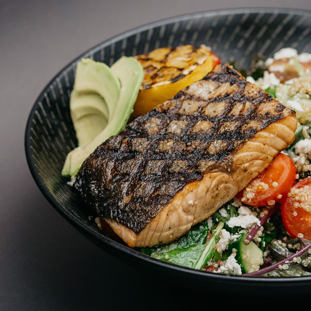 Grilled salmon on top of a salad