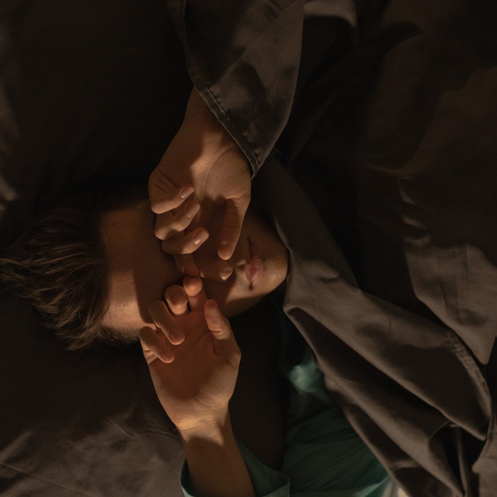 Man in Green Shirt Lying on Bed