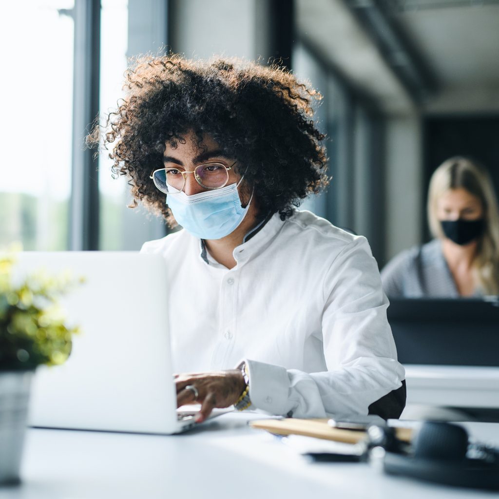 Man wearing mask working at office computer