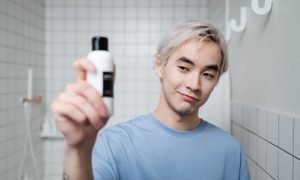 Man in Blue Crew Neck Shirt Holding White and Black Bottle