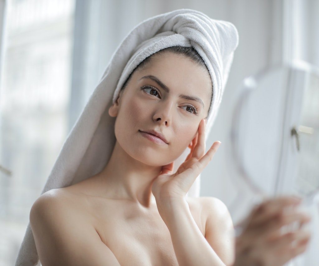 A woman checking out her face in a mirror.