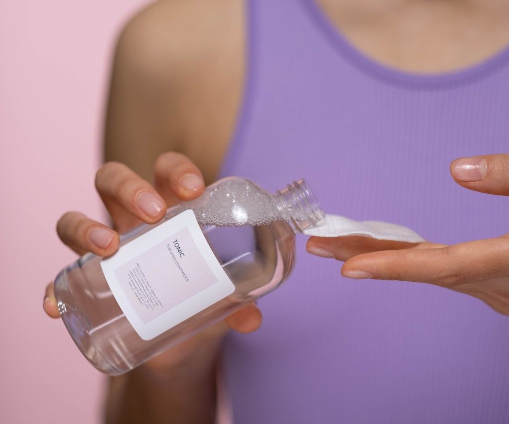 A woman putting toner on a cotton pad.