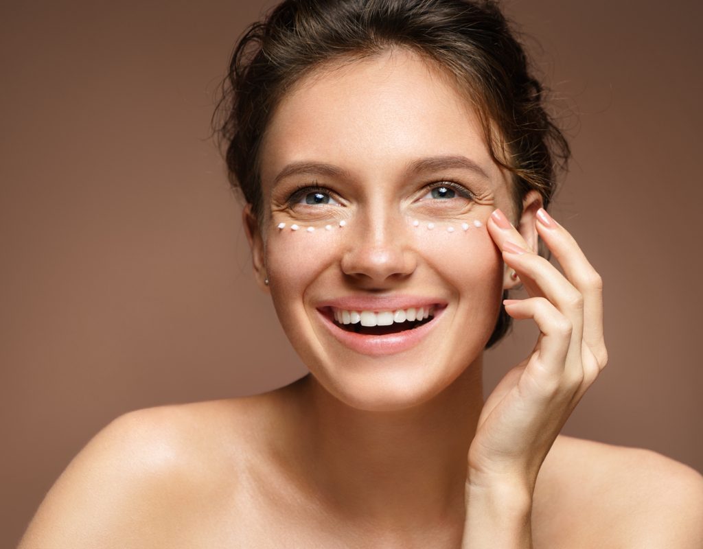 A woman putting cream under her eyes.