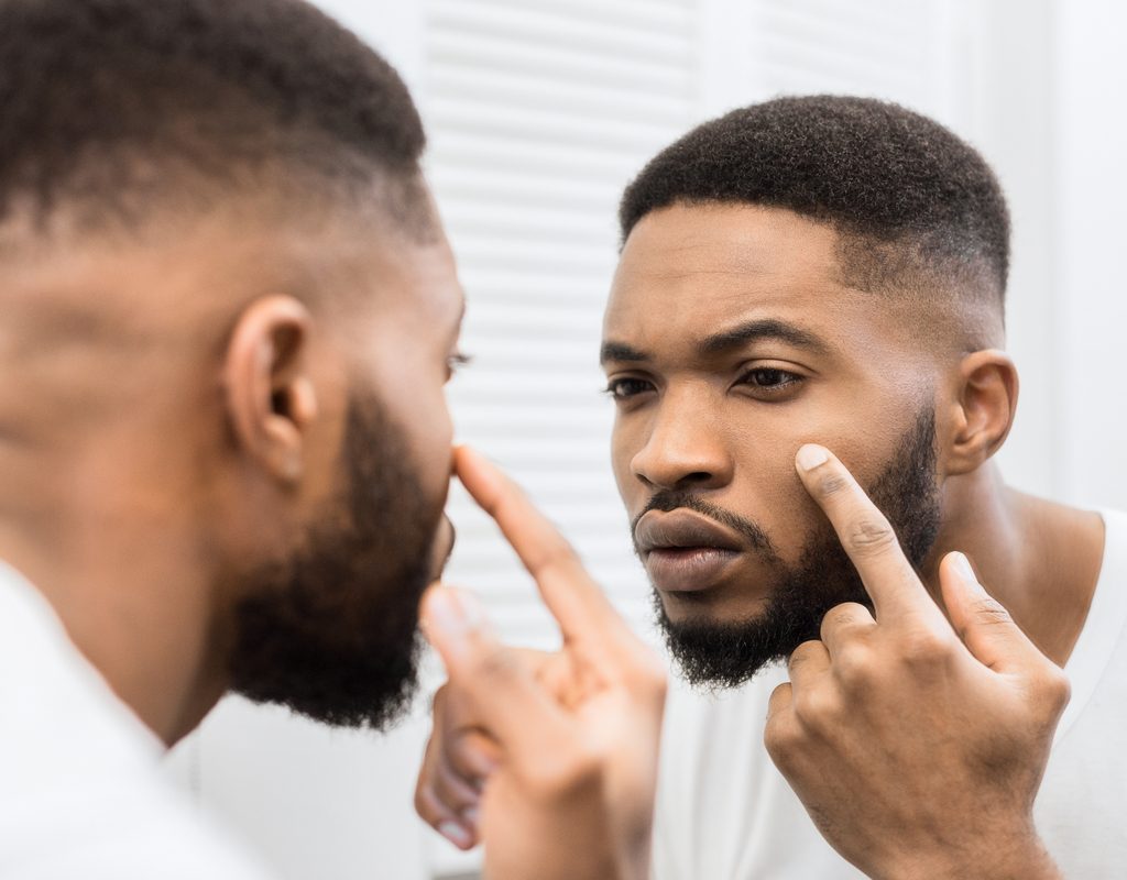 A man looking at his eyes in the mirror.