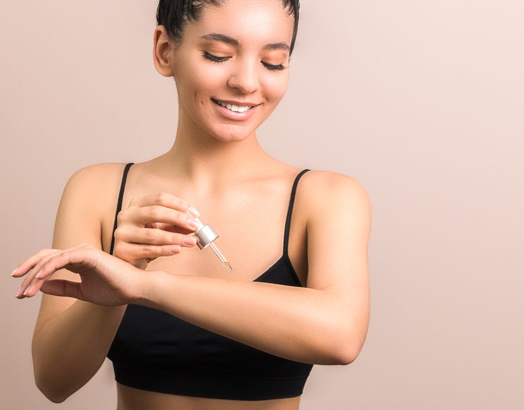 A woman putting body oil on her arm.