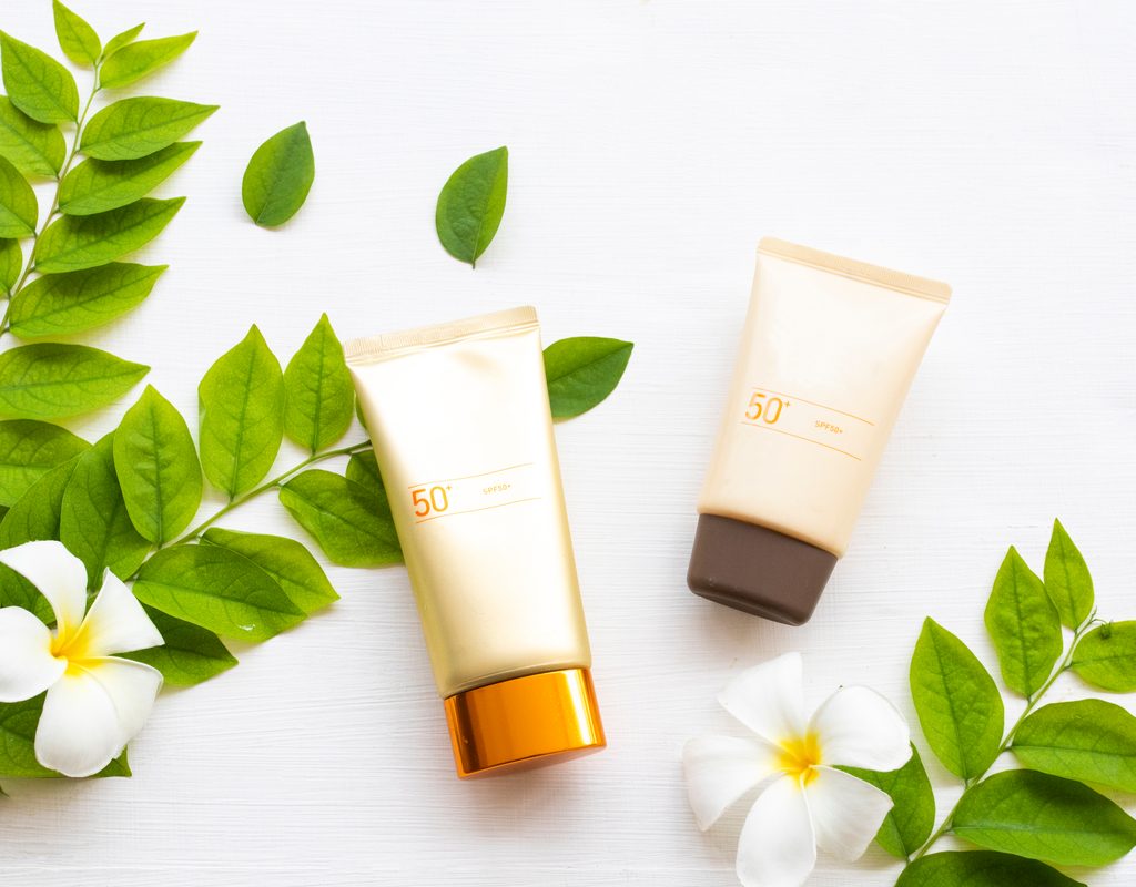 Sunscreen on a table with some green leaves.